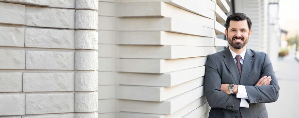 Conn Law Firm attorney in professional gray suit standing confidently outside modern office building